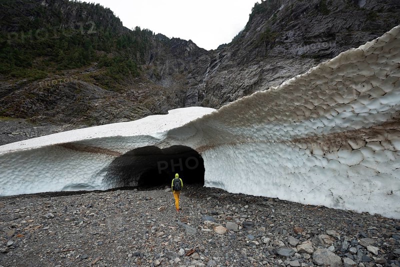 Hikers at the entrance of an ice cave of a glacier