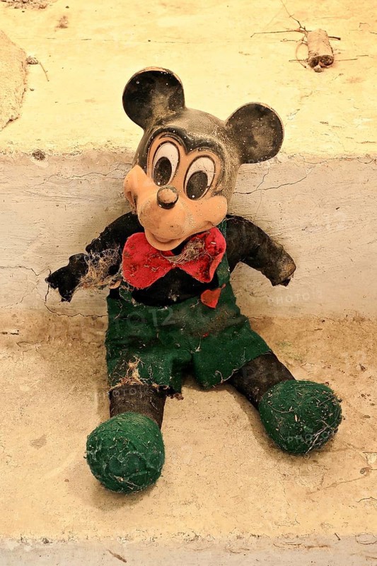 Demolished rag doll of a Mickey Mouse leaning against the wall