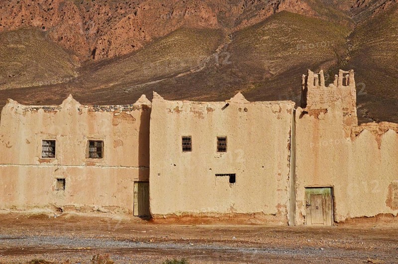 Clay fortress with tower in front of mountain wall