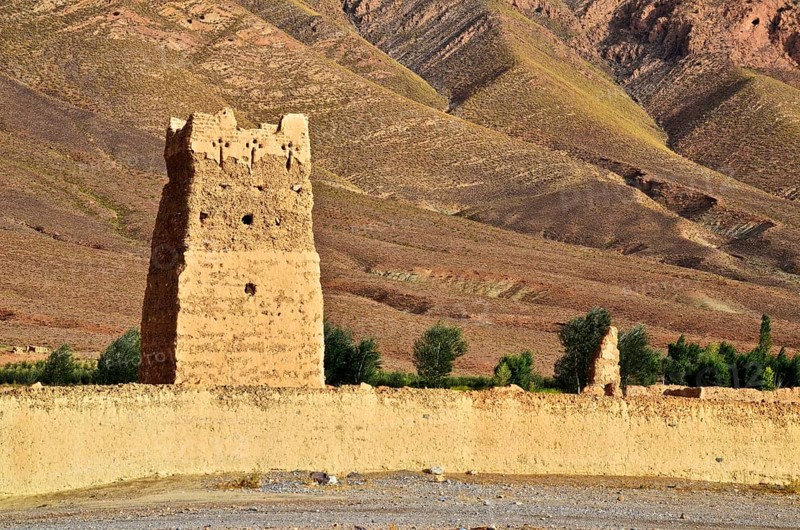 Clay fortress with tower in front of bare mountains