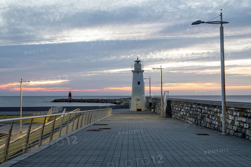 Sunrise with lighthouse at the harbour pier in Porto Maurizio