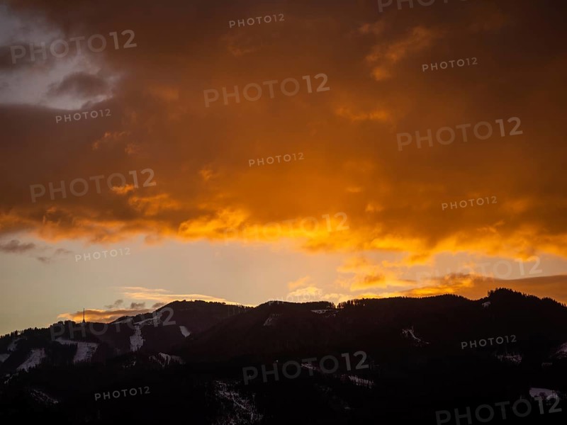 Clouds above the summit of the Mugel in the morning red at sunrise