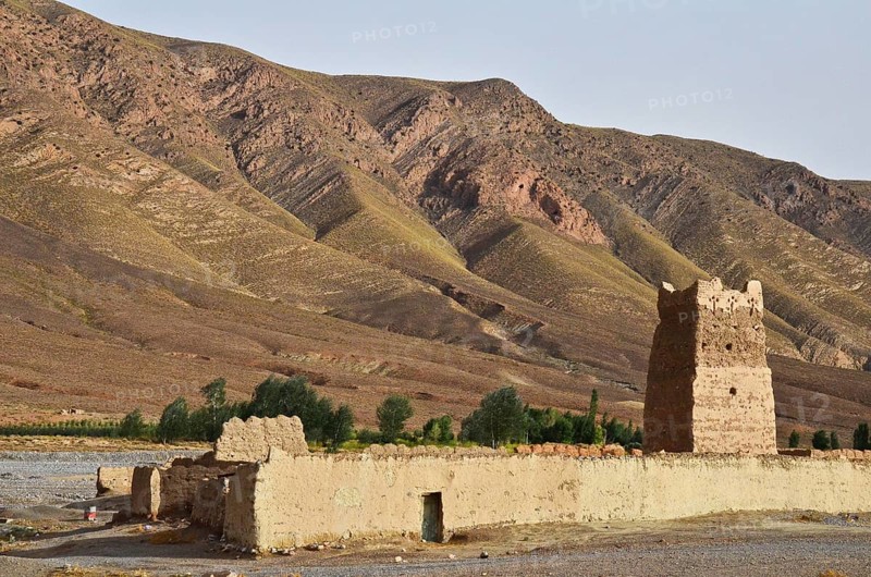 Clay fortress with tower in front of bare mountains