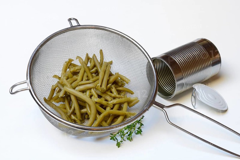 Green beans and savory in sieve and tin