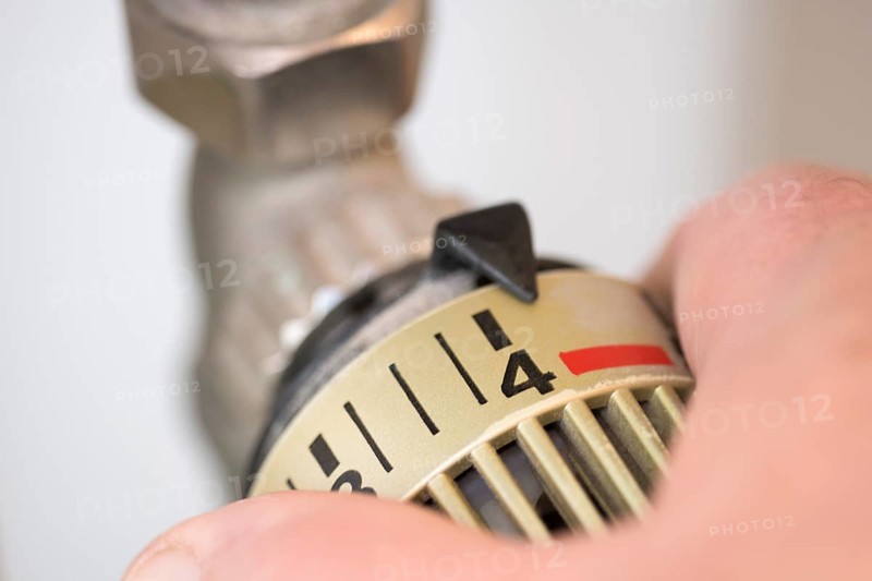 Hand on the heating thermostat