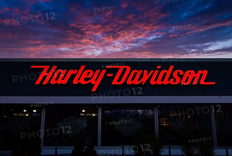 Illuminated Harley Davidson advertising sign at dusk