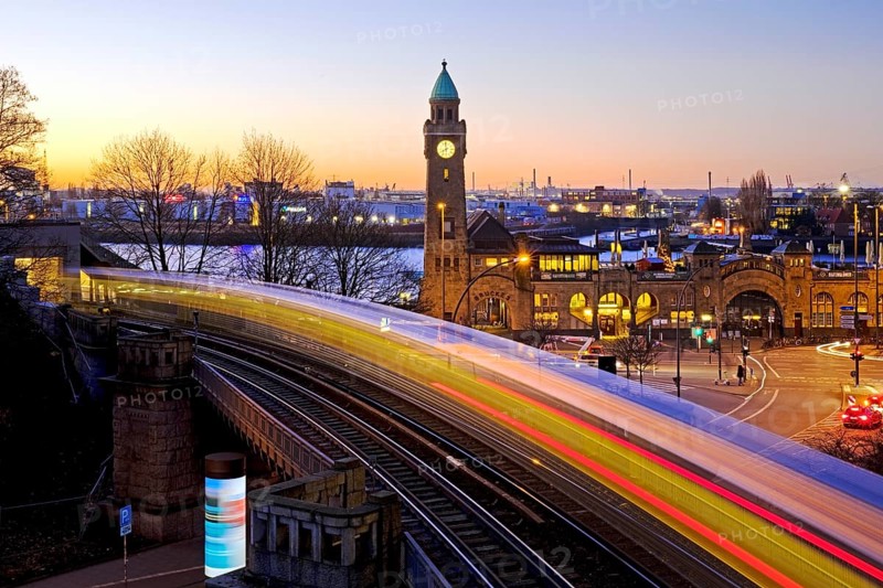 Atmospheric light trails of moving elevated railway and clock tower at sunrise
