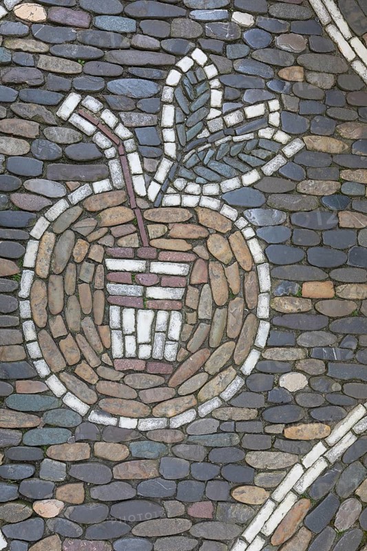 Apple and drinking cup as pavement mosaic on the pavement