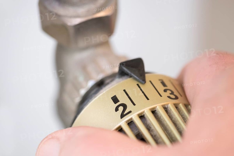 Hand on the heating thermostat