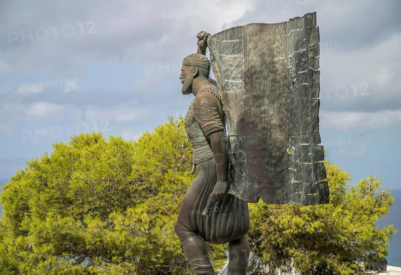 Statue and monument of Spyros Kayales with Greek flag