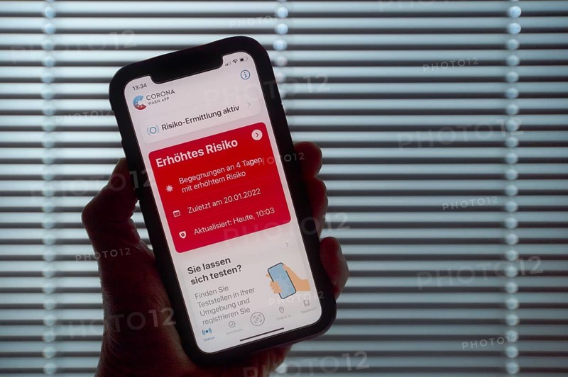Hand holding smartphone with Corona warning APP