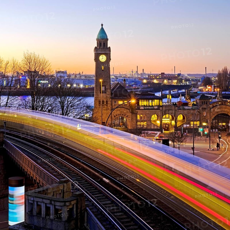 Atmospheric light trails of moving elevated railway and clock tower at sunrise