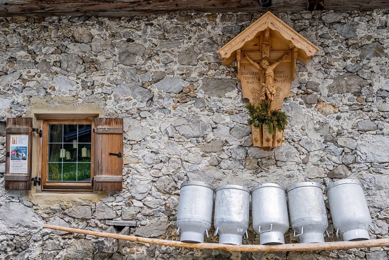 Milk cans lined up on a wooden bench