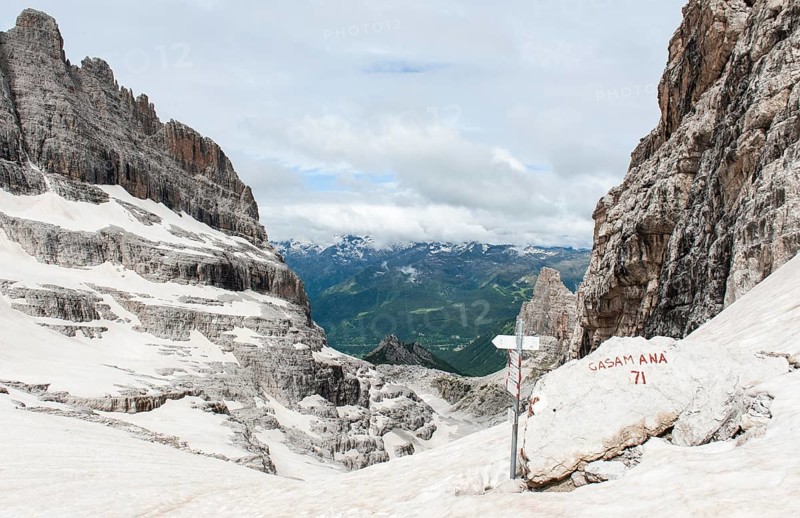 Snow-covered pass Bocca del Tuckett with hiking sign