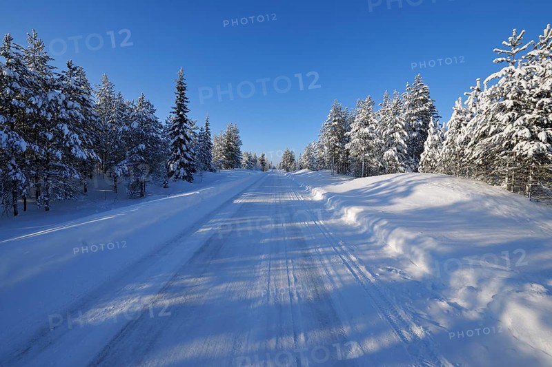 Sun over snow covered road in winter