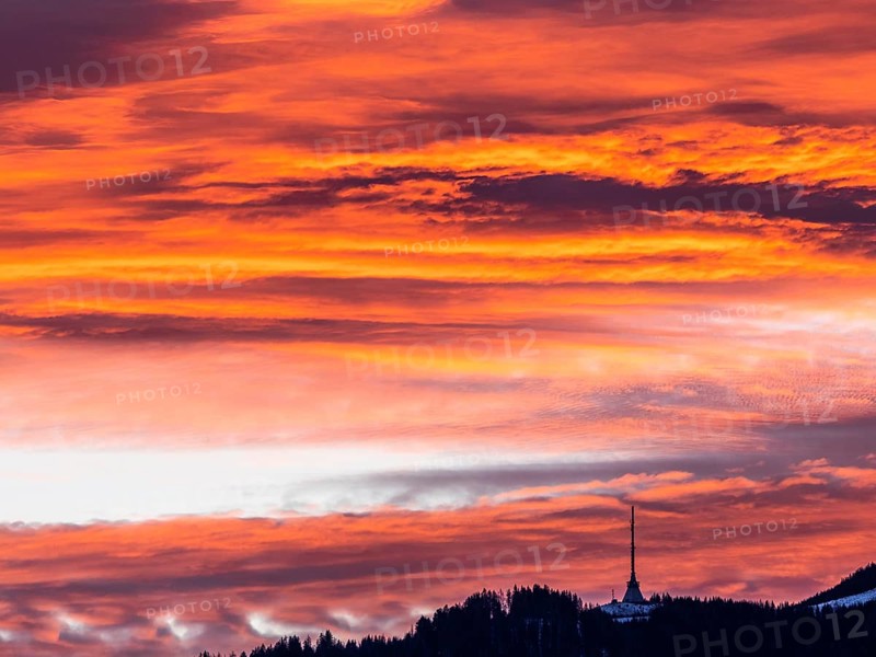 Clouds above the summit of the Mugel in the morning red at sunrise