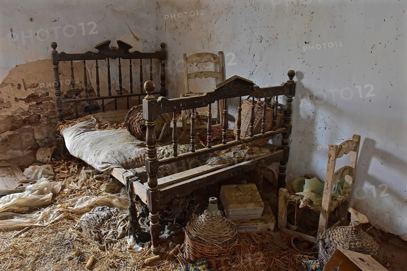 Wooden Marriage Bed with Chair and Wine Bottles in Baskets in Abandoned House