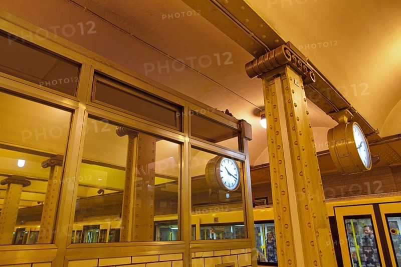 Clock reflected in a pane and steel girders of the underground station Klosterstrasse