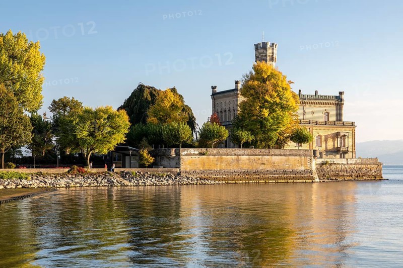 Autumn trees on the shore in the sunshine with Montfort Castle