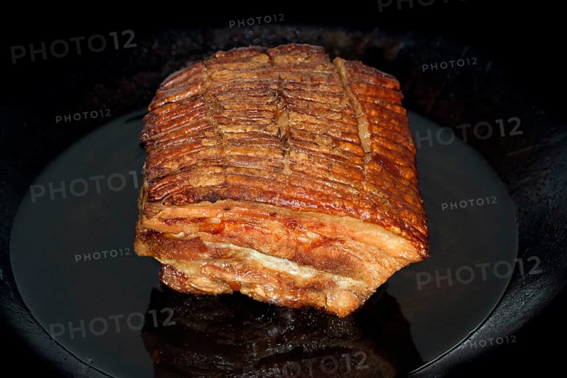 Crispy roasted pork belly lies in an iron pan