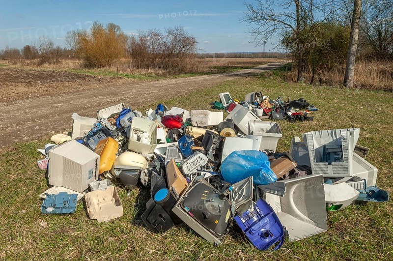 Polluting plastic waste and computer scrap illegally disposed of in a meadow
