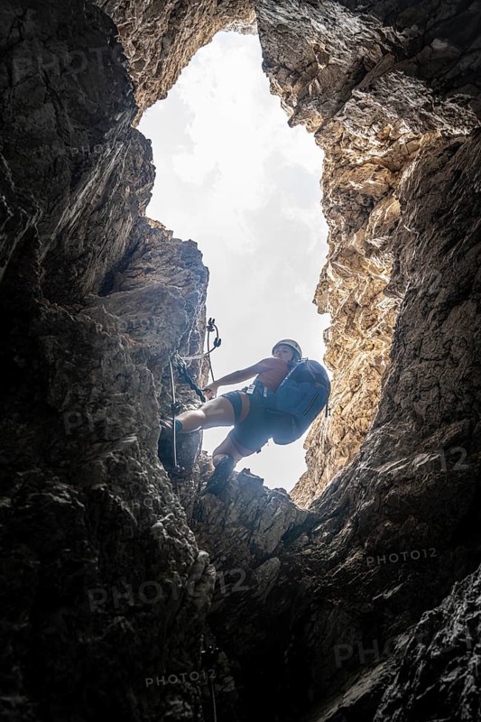 Young woman climbing a steep rock face
