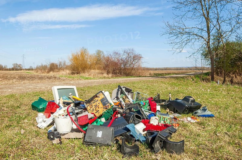 Polluting plastic waste and computer scrap illegally disposed of in a meadow