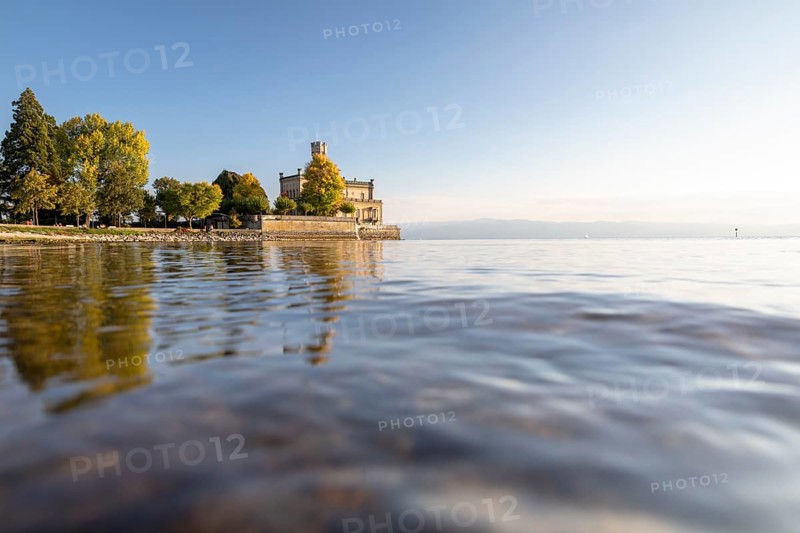 Autumn trees on the shore in the sunshine with Montfort Castle
