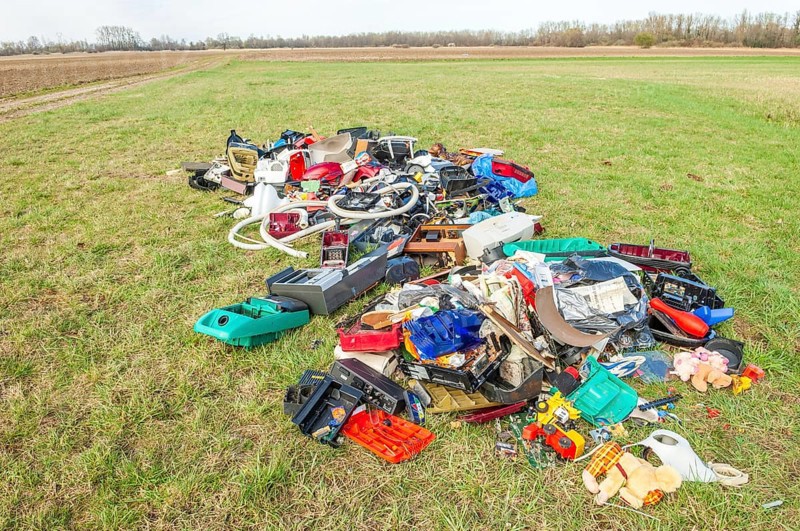 Polluting plastic waste and computer scrap illegally disposed of in a meadow