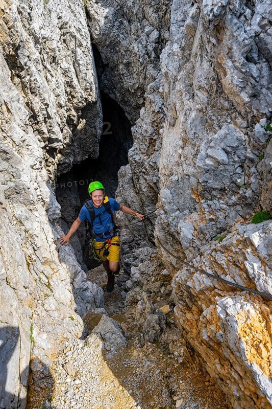 Young man climbing out of a rock hole