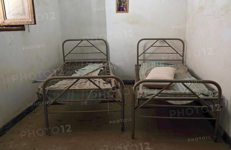 Two metal bedsteads in narrow room