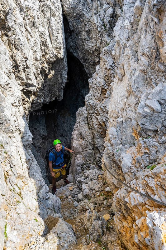 Young man climbing out of a rock hole