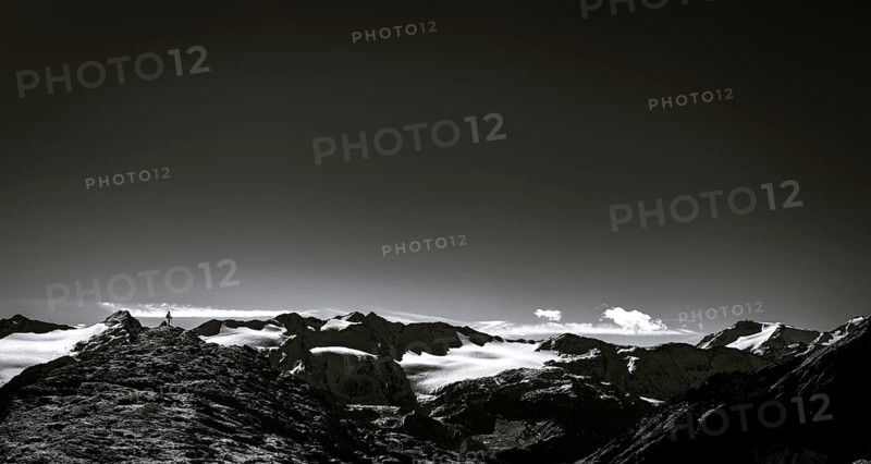 Climber on rocky outcrop with South Tyrolean mountains at blue hour