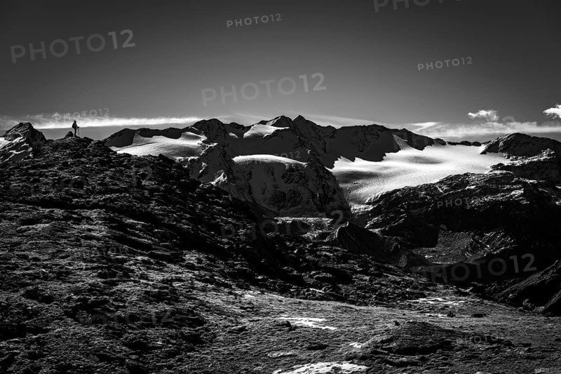 Climber on rocky outcrop with South Tyrolean mountains at blue hour
