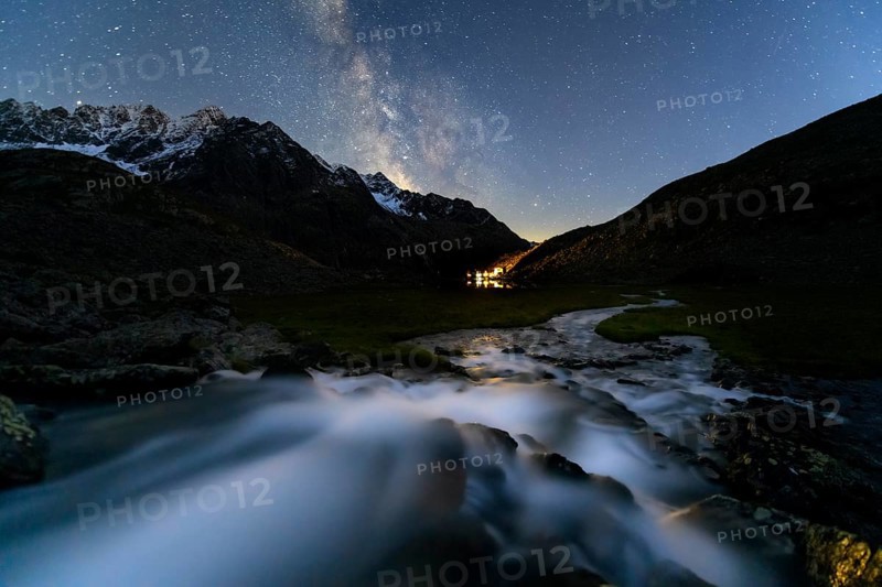 Mountain stream with Winnebachsee hut and Winnebach peaks with starry sky and Milky Way