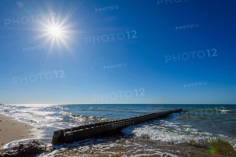 Wooden Breakwater on the Beach with Sun