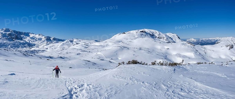 Blue sky above snowshoe hiker in winter landscape