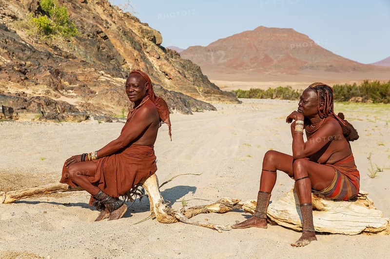 Himba women resting at the bank of the dry river bed of the Hoarusib river