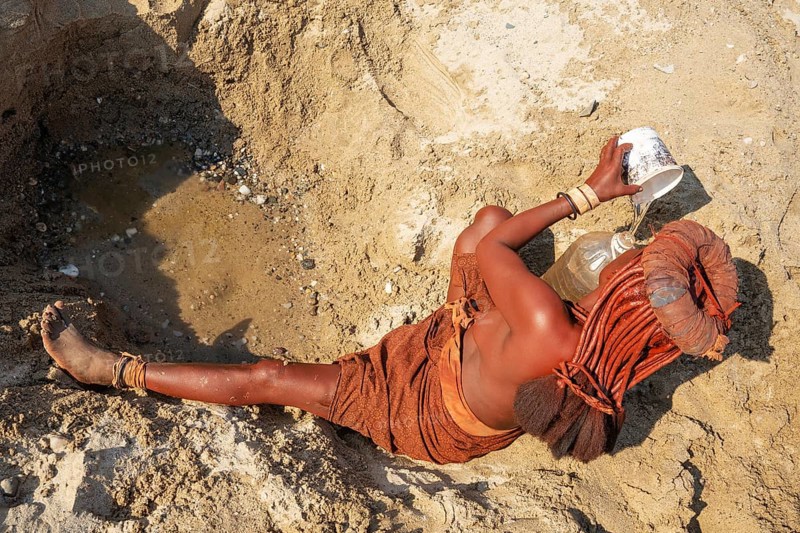 Himba woman collecting water at a water hole