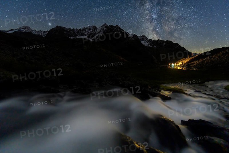 Mountain stream with Winnebachsee hut and Winnebach peaks with starry sky and Milky Way