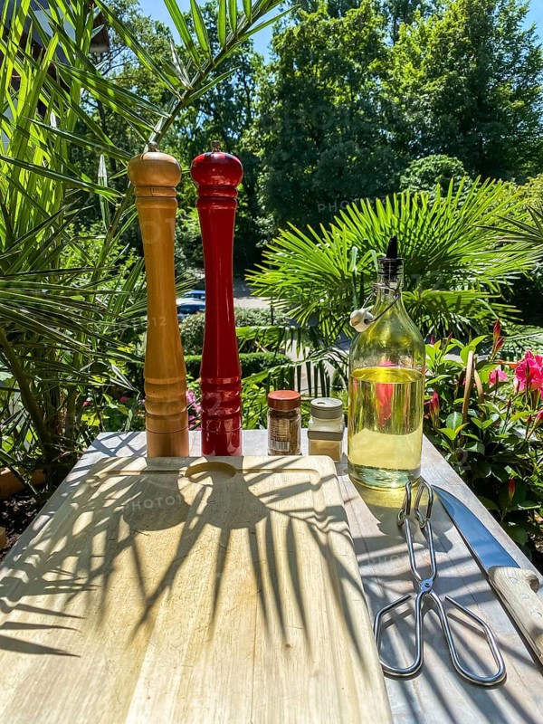 Salt and pepper mill with oil and spices in a backlit tropical garden