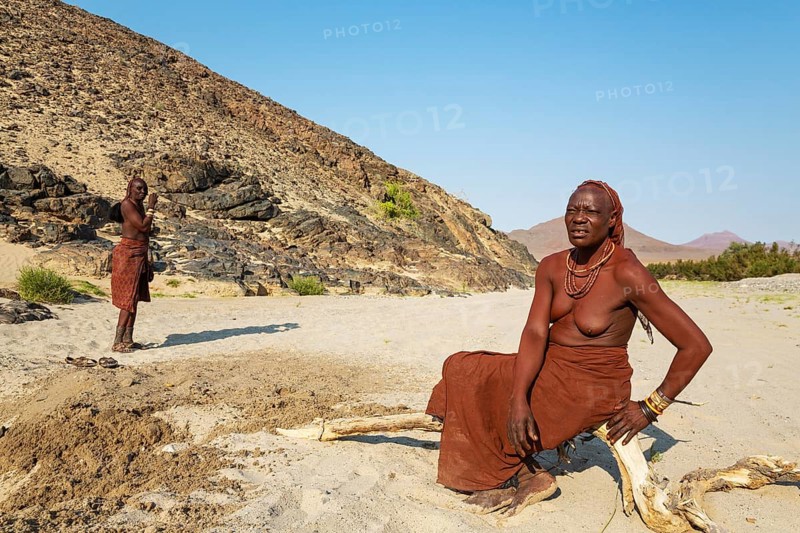 Himba women at the bank of the dry river bed of the Hoarusib river