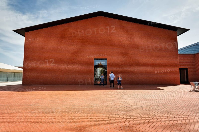 Visitors in front of building made of red bricks in the shape of a warehouse