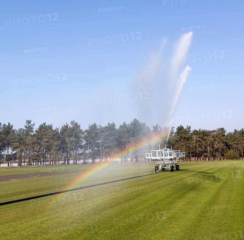 Irrigator machine spraying water turf farming