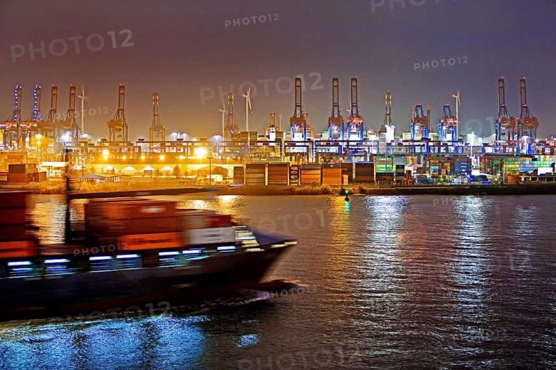 Container ship on the Norderelbe in front of loading cranes at the container terminal Burchardkai at night
