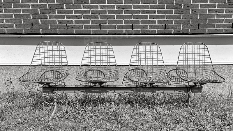 Four wire chairs in front of a wall