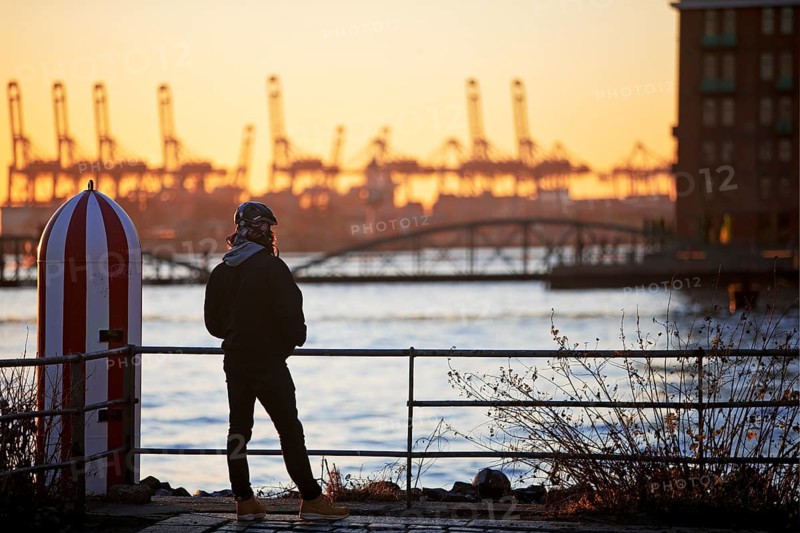 A person in front of loading cranes at the Norderelbe in Altona
