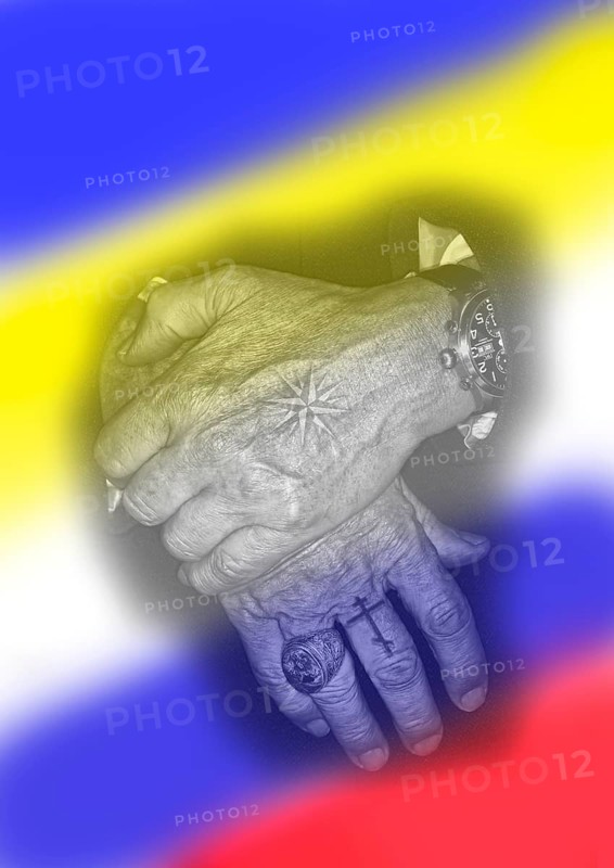Two hands with tattoos and in the background the flags of Russia and Ukraine