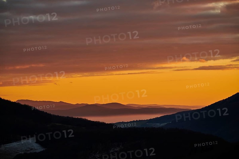 Fog lying in a valley at sunset