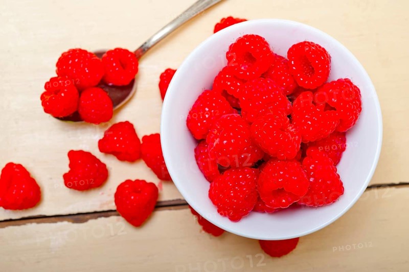 Bunch of fresh raspberry on a bowl and white wood rustic table